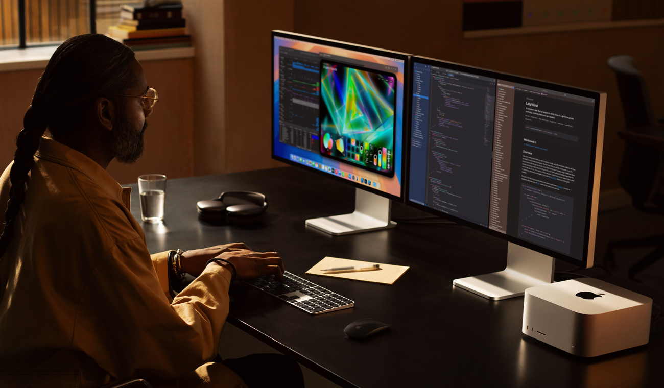 一位专业人士正在用 Mac Studio 和两台 Studio Display 显示器工作