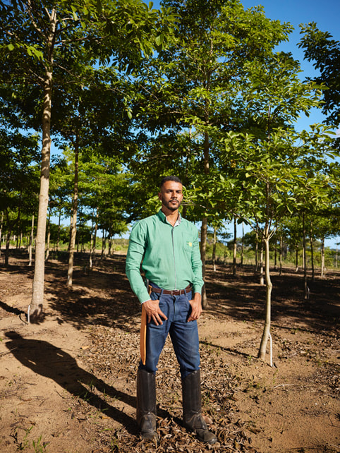 Victor Leon Rocha Araújo 穿着及膝长靴，站在大西洋森林的一排树木前。