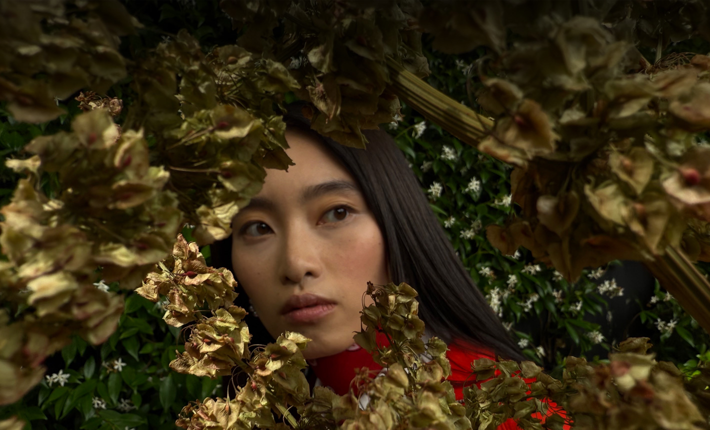 一名女子的特写照片，女子周围枝叶环绕