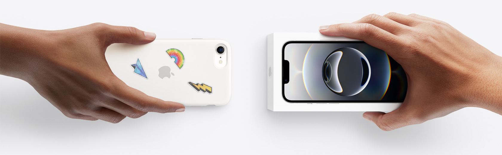 一只手拿着一部用于换购的 iPhone,换取另一只手中未拆封的新 iPhone 16e。