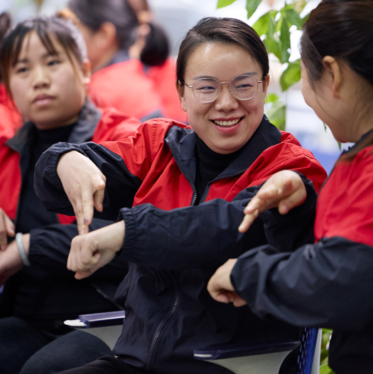 三名员工坐在一起，其中一个人正在对另一个人打手语
