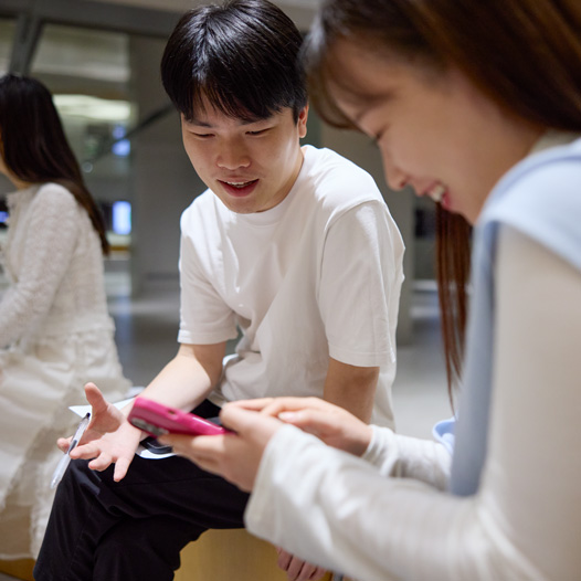 两个人边交谈边低头看着 iPhone，iPhone 由其中一个人拿着并操控